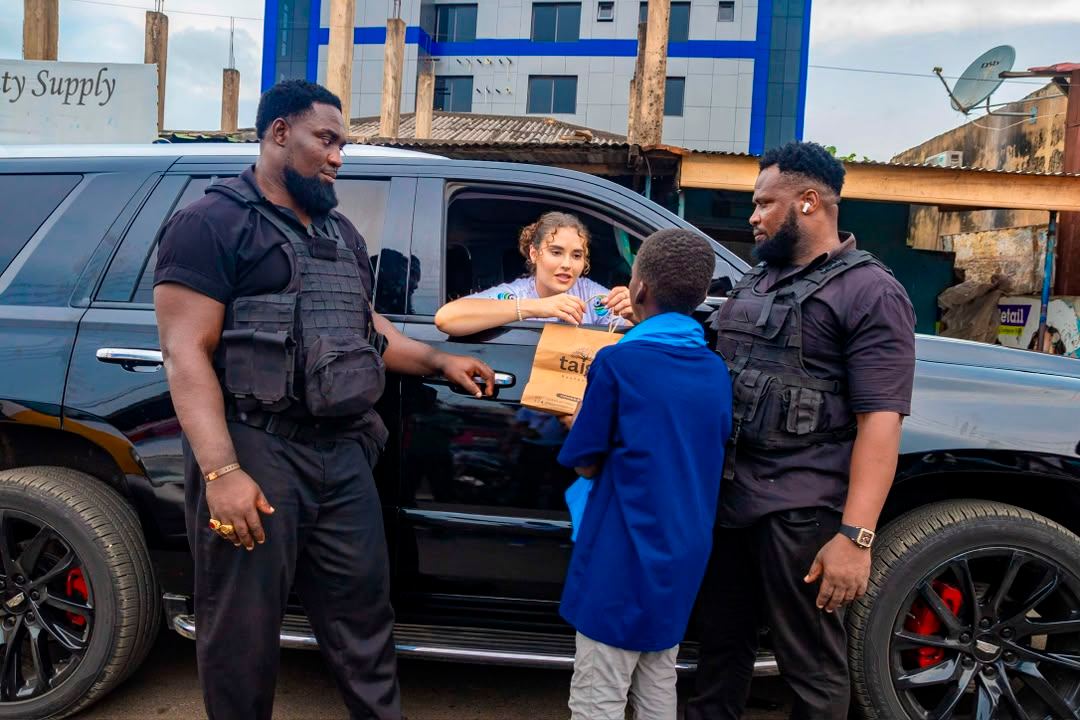 A package being handed over beside a vehicle during an outreach visit